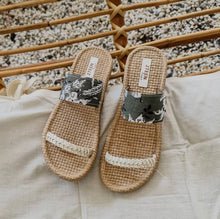 Load image into Gallery viewer, Handmade sandals with white strap and green patterns on rattan chair
